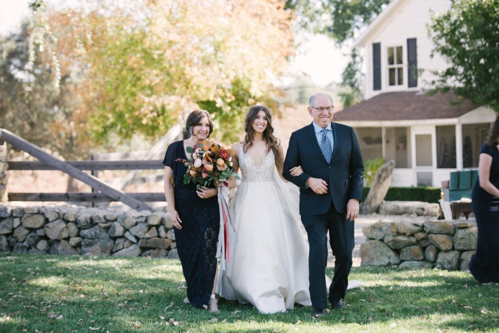 Bride is escorted down the aisle by her mother and father