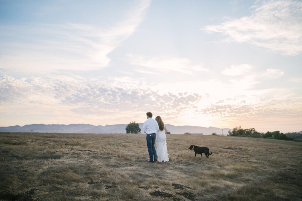 Bride and groom walk with their dog through the hills at Flying Caballos Ranch. Wedding photographer SLO