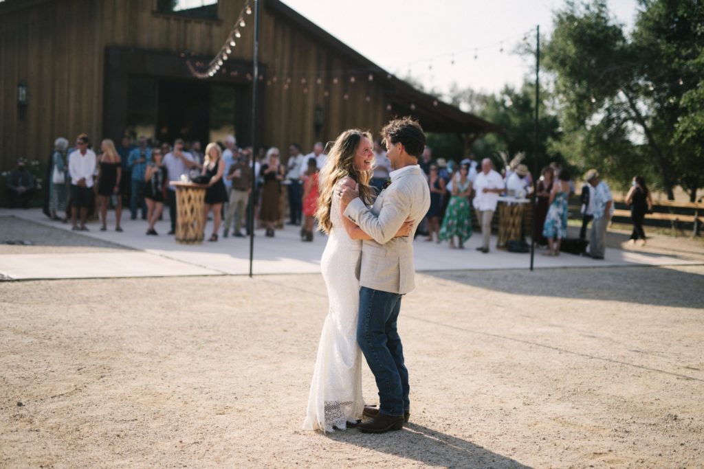 Bride and groom share their first dance in front of the barn and their guests at Flying Caballos Ranch. Wedding photographer san luis obispo